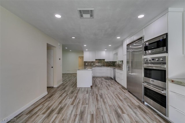 3708 Lorraine Ln, Las Vegas, NV 89120 - kitchen featuring built in appliances, recessed lighting, light wood finished floors, white cabinets, and decorative backsplash
