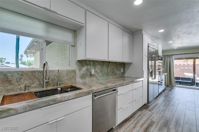 3708 Lorraine Ln, Las Vegas, NV 89120 - kitchen featuring stainless steel appliances, white cabinetry, light countertops, decorative backsplash, and light wood-style floors