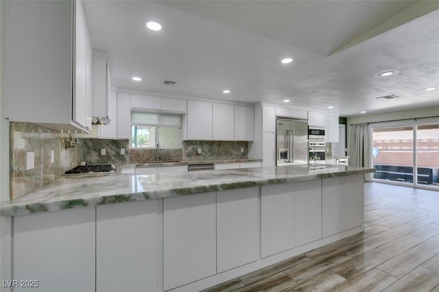 3708 Lorraine Ln, Las Vegas, NV 89120 - kitchen featuring built in appliances, white cabinets, backsplash, light stone countertops, and light wood-style floors