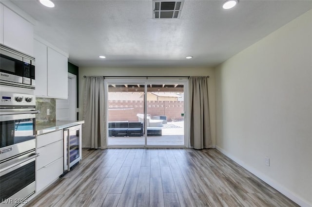 3708 Lorraine Ln, Las Vegas, NV 89120 - kitchen featuring beverage cooler, stainless steel appliances, light wood-style flooring, white cabinetry, and recessed lighting