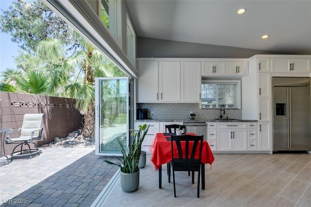 3708 Lorraine Ln, Las Vegas, NV 89120 - kitchen with appliances with stainless steel finishes, vaulted ceiling, tasteful backsplash, white cabinetry, and light stone countertops