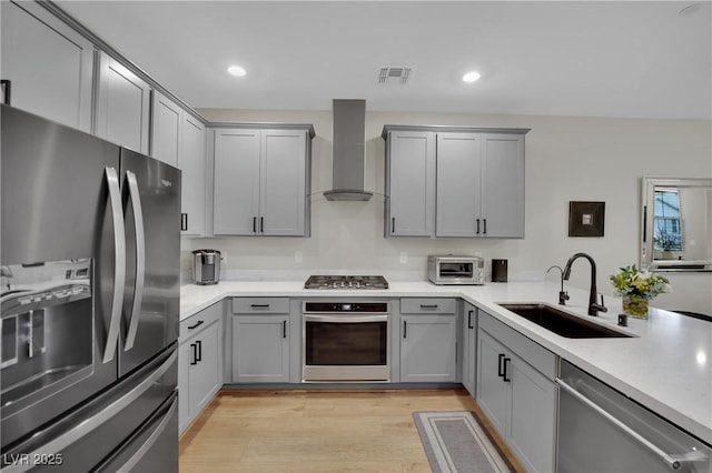 530 Sonoma Range St, Las Vegas, NV 89138 - kitchen featuring appliances with stainless steel finishes, gray cabinetry, wall chimney range hood, light wood-style flooring, and recessed lighting