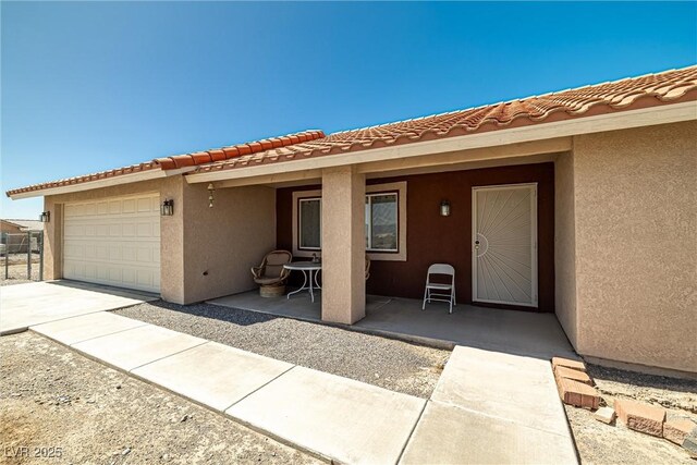 2730 Banyon St, Pahrump, NV 89048 - entrance to property featuring stucco siding, a garage, concrete driveway, a tile roof, and a patio area