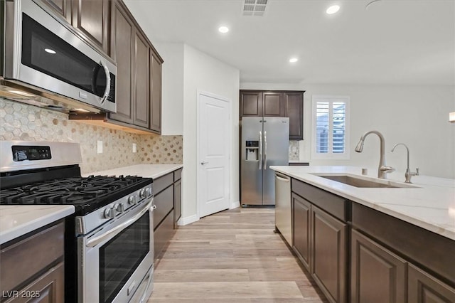 9327 Ettrick Ct, Las Vegas, NV 89178 - kitchen featuring appliances with stainless steel finishes, dark brown cabinets, light wood-type flooring, backsplash, and recessed lighting