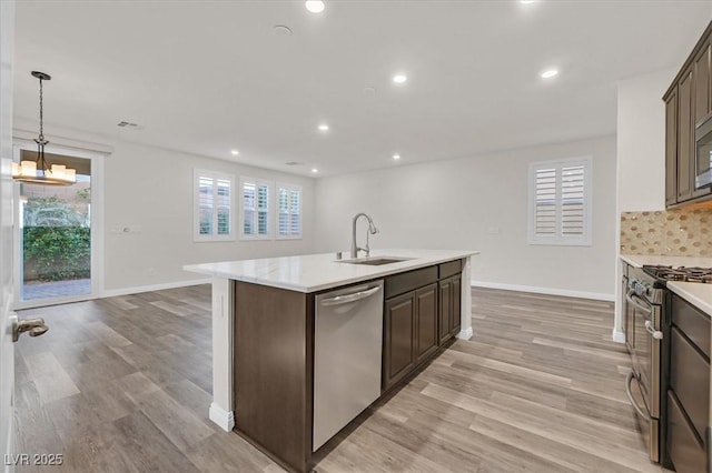 9327 Ettrick Ct, Las Vegas, NV 89178 - kitchen with stainless steel appliances, light countertops, decorative backsplash, light wood-style flooring, and dark brown cabinetry