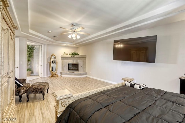 9905 Fox Springs Dr, Las Vegas, NV 89117 - bedroom with wood finished floors, a tray ceiling, a tiled fireplace, and ceiling fan