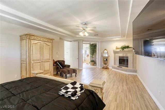 9905 Fox Springs Dr, Las Vegas, NV 89117 - bedroom with a tray ceiling, light wood-type flooring, a tiled fireplace, and ceiling fan