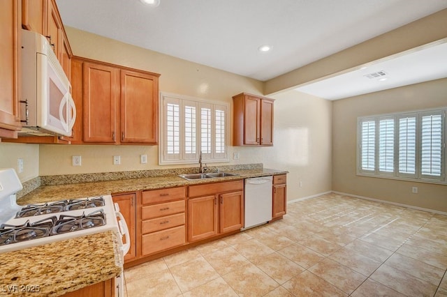 7916 Lyrebird Dr, North Las Vegas, NV 89084 - kitchen with white appliances, recessed lighting, brown cabinetry, light stone counters, and light tile patterned flooring