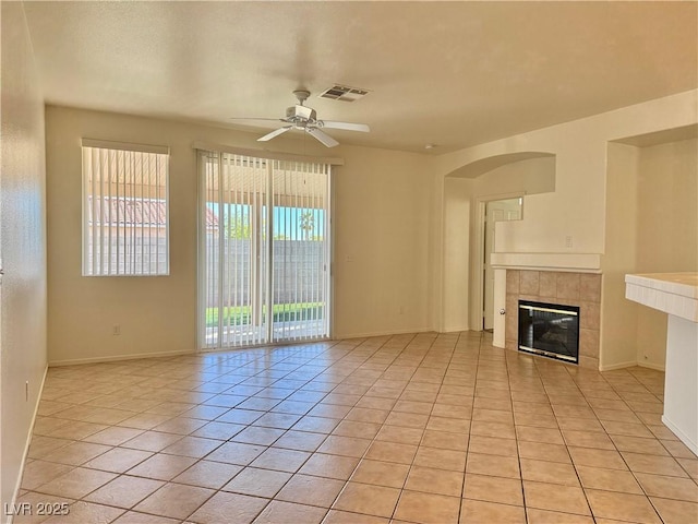 338 Brilliant Summit Cir, Henderson, NV 89052 - unfurnished living room featuring ceiling fan, light tile patterned flooring, a tiled fireplace, and arched walkways