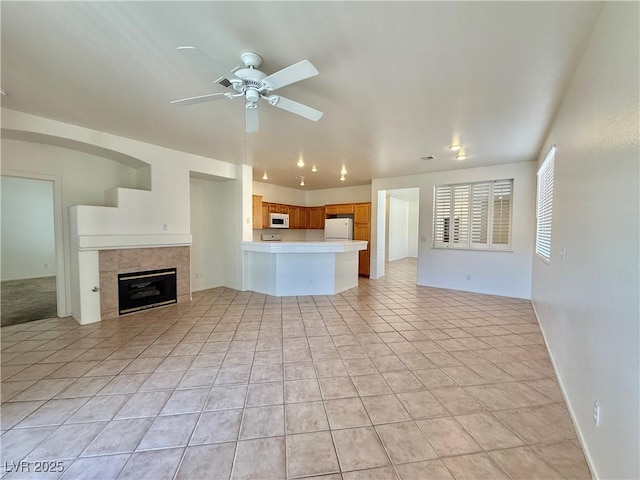 338 Brilliant Summit Cir, Henderson, NV 89052 - unfurnished living room with ceiling fan, light tile patterned floors, and a tile fireplace