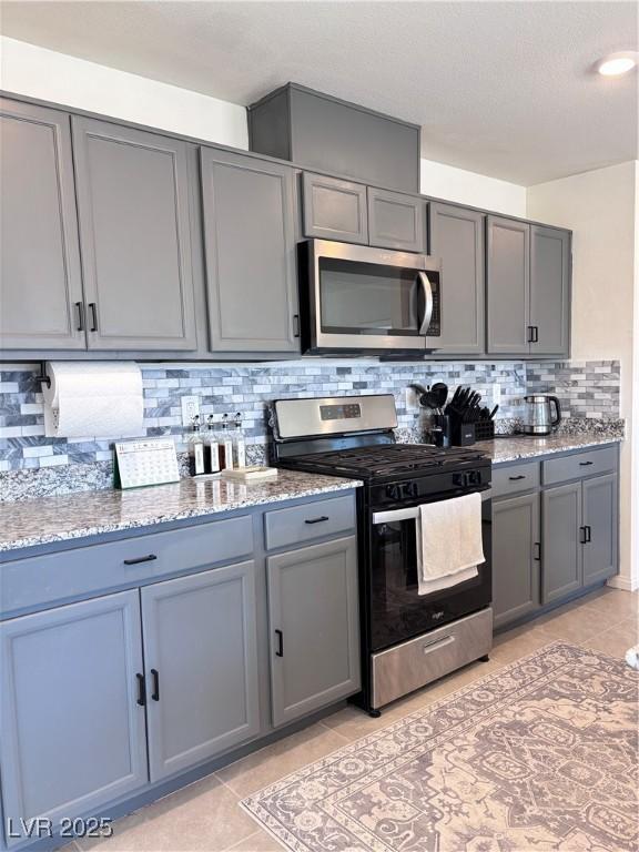 4993 Birchland Manor Ave, Las Vegas, NV 89139 - kitchen with stainless steel appliances, gray cabinetry, and light tile patterned flooring