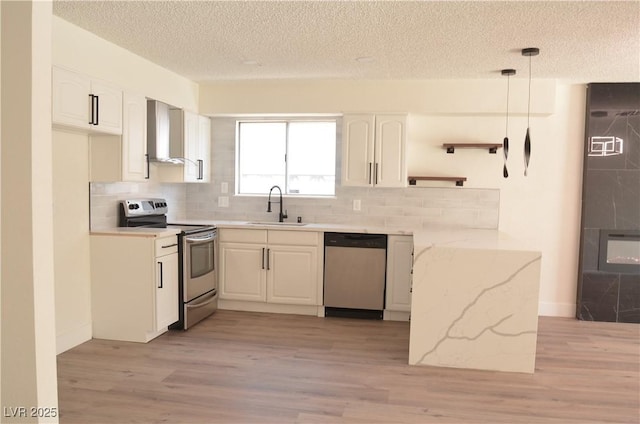 4277 Rimcrest Rd, Las Vegas, NV 89121 - kitchen with stainless steel appliances, wall chimney exhaust hood, a textured ceiling, light wood finished floors, and white cabinets