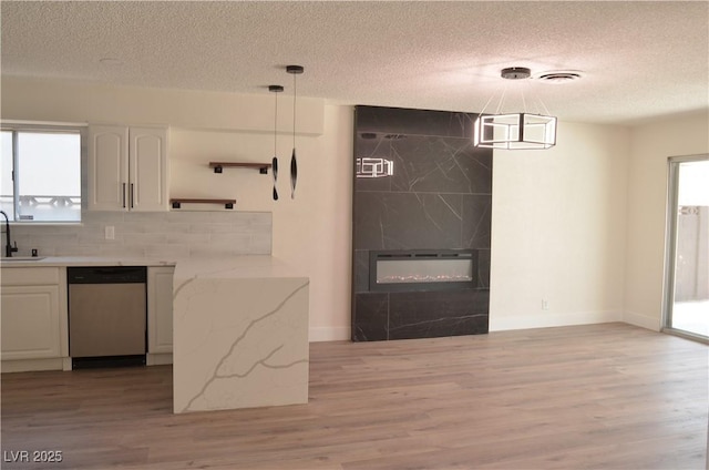 4277 Rimcrest Rd, Las Vegas, NV 89121 - kitchen with stainless steel dishwasher, a textured ceiling, light wood finished floors, white cabinetry, and light stone countertops