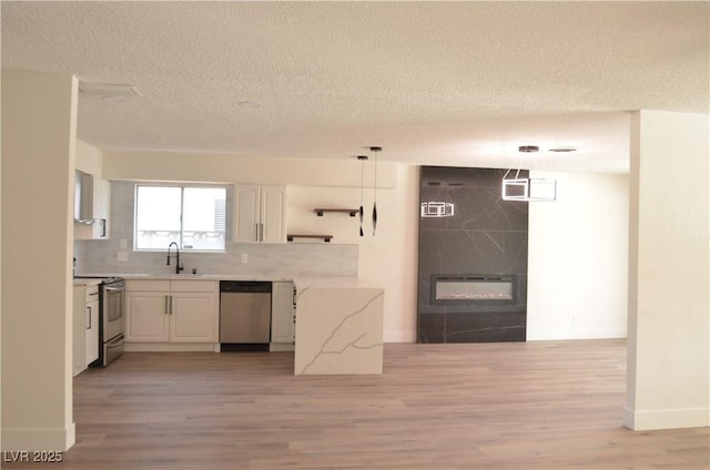 4277 Rimcrest Rd, Las Vegas, NV 89121 - kitchen with stainless steel appliances, light wood-type flooring, a textured ceiling, white cabinets, and tasteful backsplash
