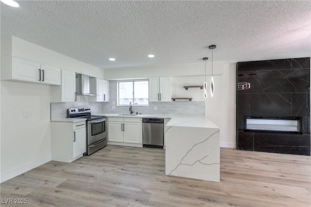 4277 Rimcrest Rd, Las Vegas, NV 89121 - kitchen with stainless steel appliances, wall chimney range hood, a textured ceiling, recessed lighting, and white cabinetry