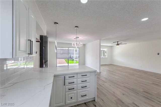 4277 Rimcrest Rd, Las Vegas, NV 89121 - kitchen with open floor plan, a peninsula, ceiling fan, a textured ceiling, and light stone counters