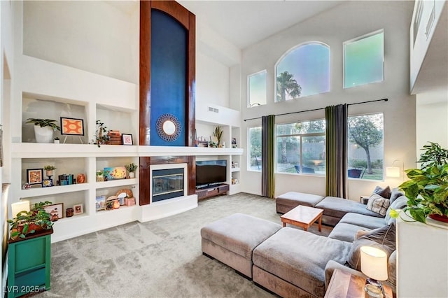8812 Glenistar Gate Ave, Las Vegas, NV 89143 - living area featuring a high ceiling, carpet, a glass covered fireplace, and built in shelves