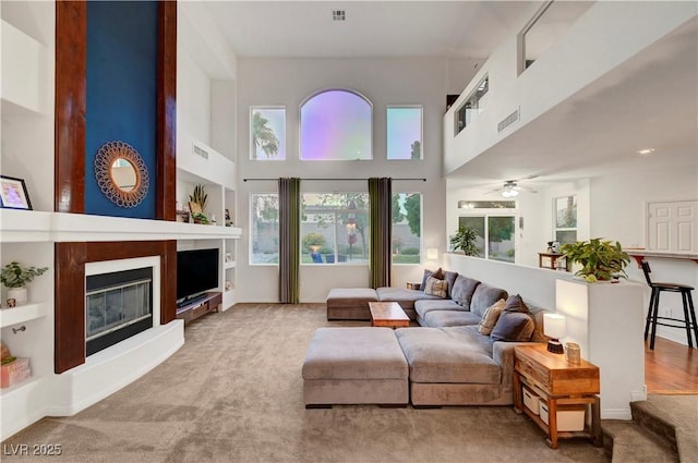 8812 Glenistar Gate Ave, Las Vegas, NV 89143 - carpeted living area with a towering ceiling, a large fireplace, healthy amount of natural light, and ceiling fan