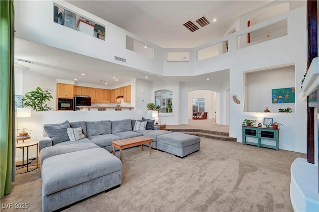 8812 Glenistar Gate Ave, Las Vegas, NV 89143 - living room featuring arched walkways, a high ceiling, light colored carpet, and recessed lighting