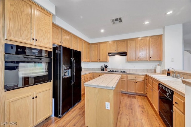 8812 Glenistar Gate Ave, Las Vegas, NV 89143 - kitchen featuring black appliances, light brown cabinetry, tile countertops, under cabinet range hood, and light wood-type flooring