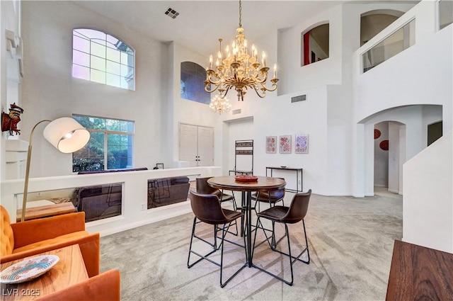 8812 Glenistar Gate Ave, Las Vegas, NV 89143 - dining space featuring light carpet, a towering ceiling, arched walkways, and a chandelier