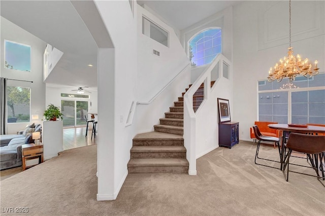 8812 Glenistar Gate Ave, Las Vegas, NV 89143 - stairs featuring a chandelier, a high ceiling, carpet flooring, arched walkways, and a ceiling fan