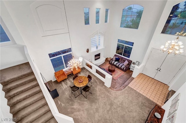 8812 Glenistar Gate Ave, Las Vegas, NV 89143 - living area with stairs, a chandelier, a fireplace, and a towering ceiling