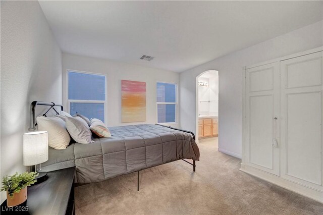 8812 Glenistar Gate Ave, Las Vegas, NV 89143 - bedroom with arched walkways, light colored carpet, and ensuite bath