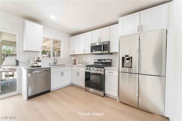 1700 Sweeney Ave, Las Vegas, NV 89104 - kitchen with appliances with stainless steel finishes, light countertops, white cabinetry, light wood-type flooring, and recessed lighting