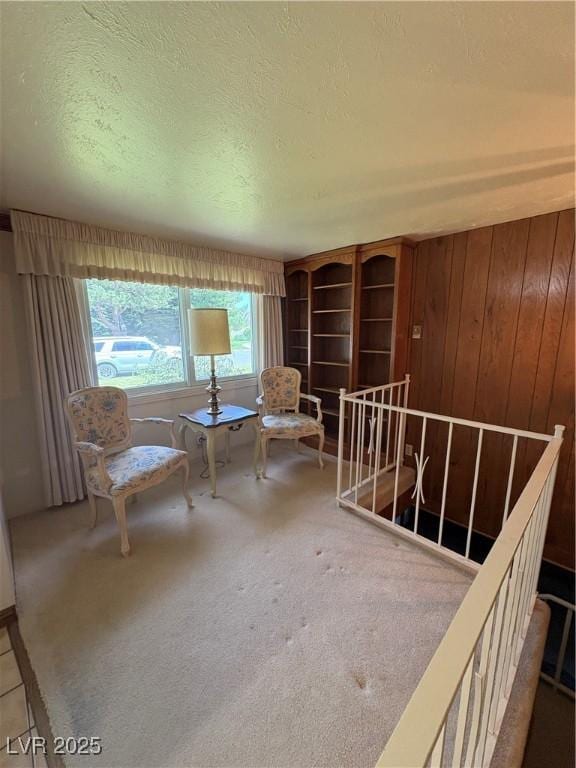 1133 Bell Ave, Ely, NV 89301 - living area featuring carpet, wood walls, a textured ceiling, and an upstairs landing
