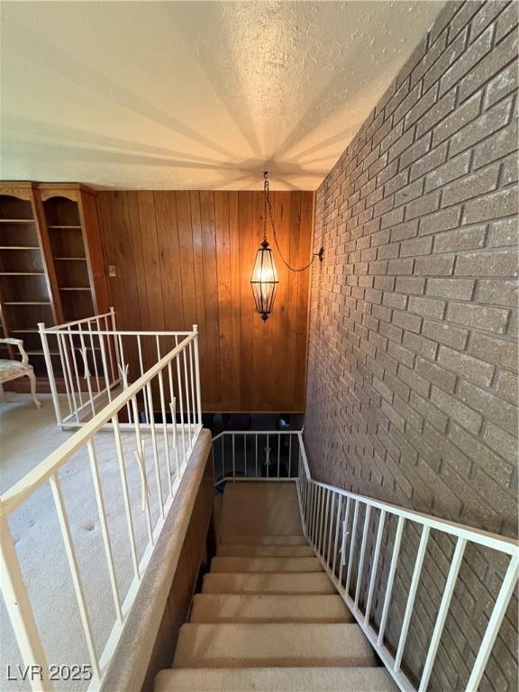 1133 Bell Ave, Ely, NV 89301 - stairway featuring brick wall, a textured ceiling, and wooden walls