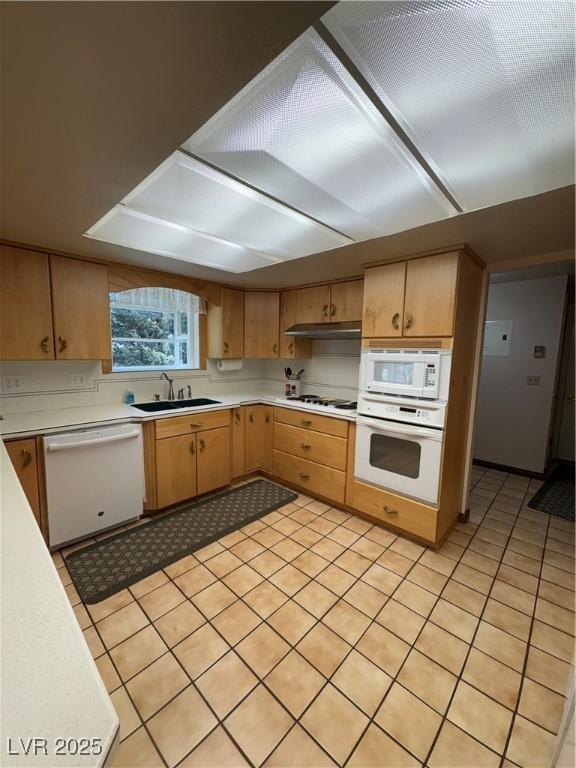 1133 Bell Ave, Ely, NV 89301 - kitchen featuring white appliances, light countertops, under cabinet range hood, light tile patterned floors, and light brown cabinetry