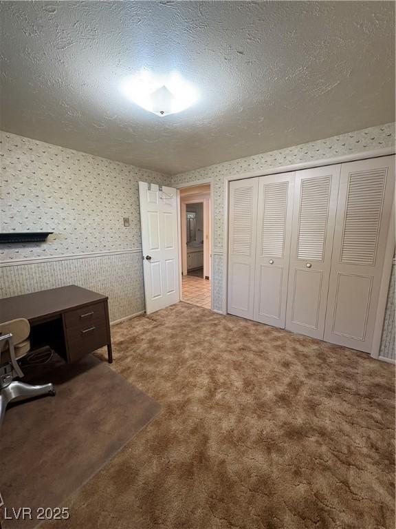 1133 Bell Ave, Ely, NV 89301 - unfurnished bedroom with wallpapered walls, carpet floors, a closet, and a textured ceiling