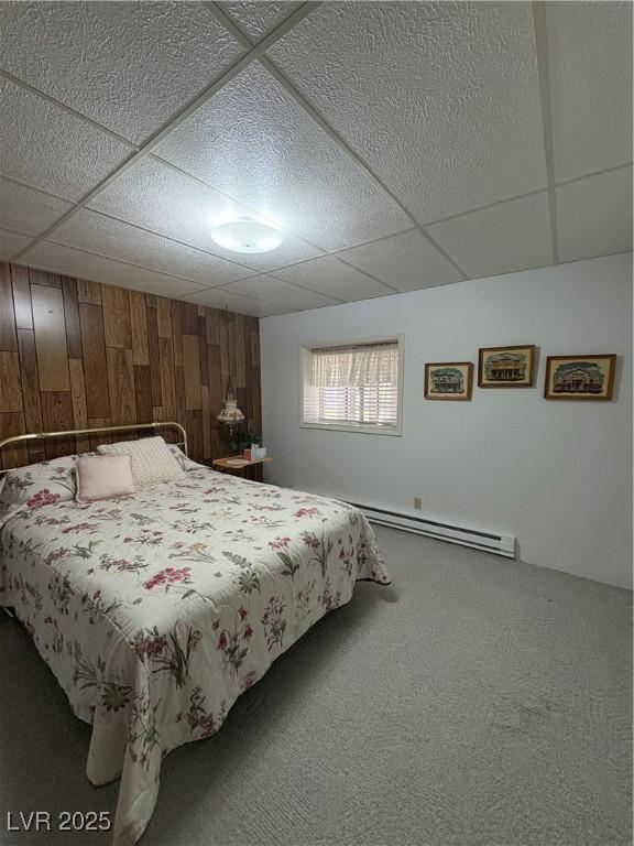 1133 Bell Ave, Ely, NV 89301 - bedroom featuring baseboard heating, a drop ceiling, carpet flooring, and wooden walls