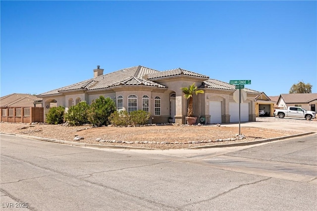 467 Muddy Peak Ct, Overton, NV 89040 - mediterranean / spanish-style home with a garage, stucco siding, a chimney, a tiled roof, and driveway