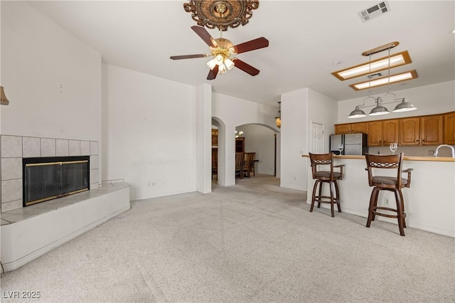 467 Muddy Peak Ct, Overton, NV 89040 - living room featuring arched walkways, light carpet, a ceiling fan, and a fireplace