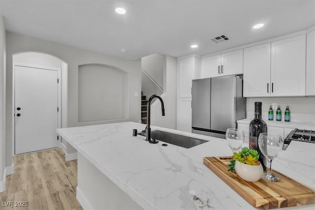10373 Midnight Iris St, Las Vegas, NV 89183 - kitchen with freestanding refrigerator, light stone counters, white cabinetry, light wood-style flooring, and recessed lighting