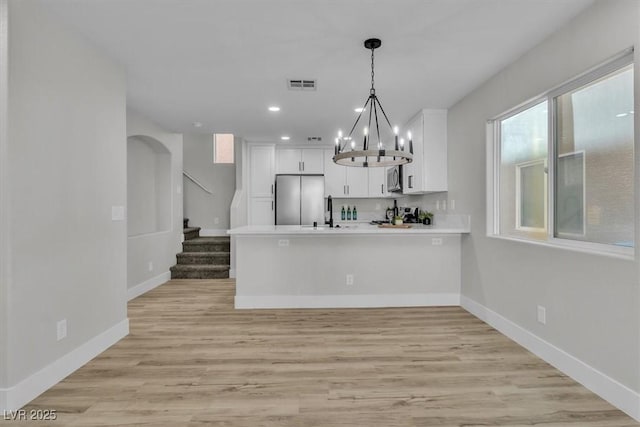 10373 Midnight Iris St, Las Vegas, NV 89183 - kitchen with appliances with stainless steel finishes, a peninsula, white cabinets, a chandelier, and recessed lighting