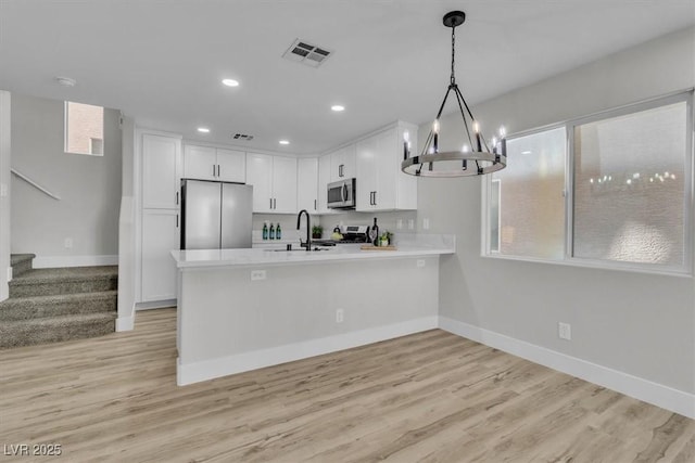 10373 Midnight Iris St, Las Vegas, NV 89183 - kitchen featuring stainless steel appliances, a peninsula, a chandelier, light countertops, and white cabinetry