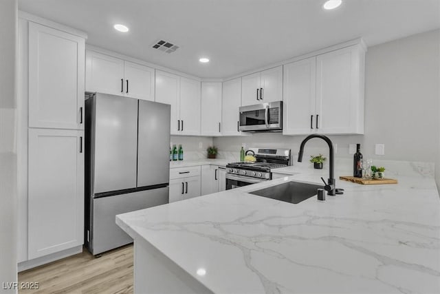 10373 Midnight Iris St, Las Vegas, NV 89183 - kitchen featuring appliances with stainless steel finishes, light stone countertops, white cabinets, recessed lighting, and light wood-type flooring