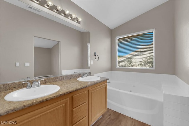 1553 Ivygate Ave, Las Vegas, NV 89183 - bathroom featuring a jetted tub, lofted ceiling, double vanity, and wood finished floors