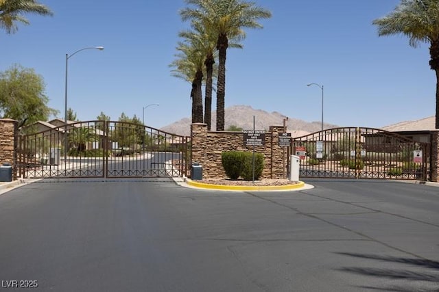 5935 Saddle Horse Ave, Las Vegas, NV 89122 - view of asphalt street with a gate, street lights, and a mountain view
