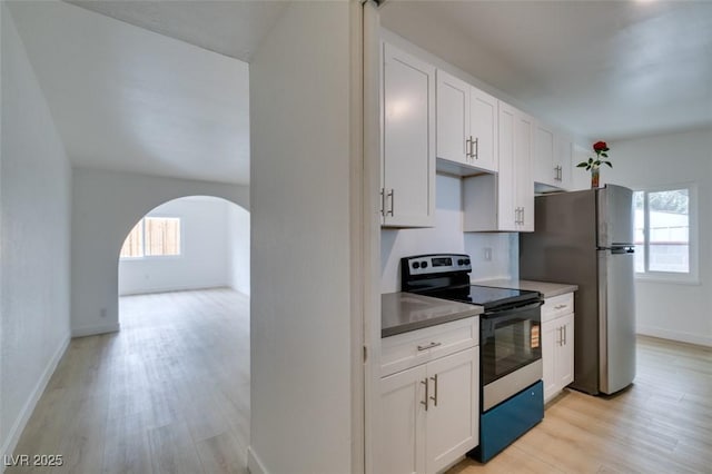 709 N 22nd St, Las Vegas, NV 89101 - kitchen featuring stainless steel appliances, arched walkways, light wood-style floors, and white cabinets