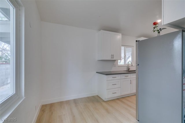 709 N 22nd St, Las Vegas, NV 89101 - kitchen with freestanding refrigerator, light wood-style floors, white cabinets, and dark countertops
