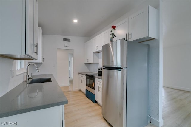 709 N 22nd St, Las Vegas, NV 89101 - kitchen with appliances with stainless steel finishes, light wood-style flooring, white cabinetry, recessed lighting, and dark stone countertops