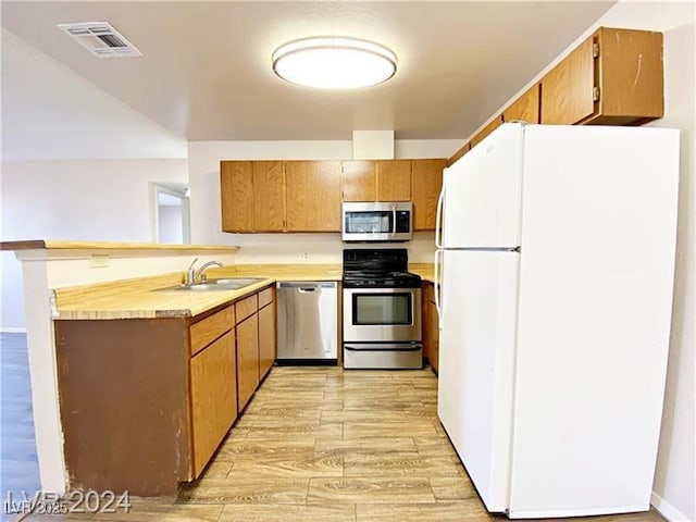 2705 Jennydiane Dr, Las Vegas, NV 89121 - kitchen with appliances with stainless steel finishes, light wood-style floors, a peninsula, light countertops, and brown cabinetry