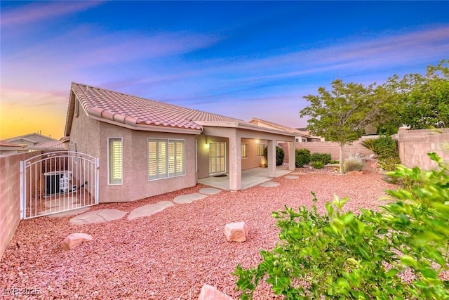 1643 Silver Slipper Ave, Henderson, NV 89002 - back of house at dusk featuring stucco siding, a gate, a patio area, and a tiled roof
