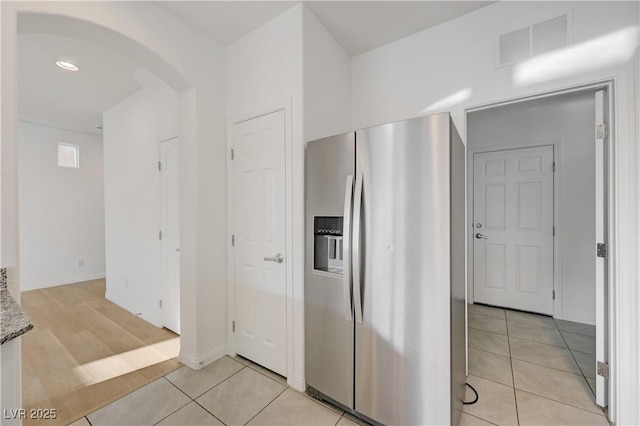 7775 Tyrell Peaks St, Las Vegas, NV 89139 - kitchen with stainless steel fridge, arched walkways, light tile patterned flooring, and stone counters