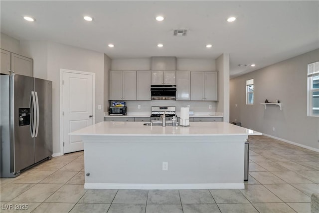 10630 Adobe Ranch St, Las Vegas, NV 89141 - kitchen with appliances with stainless steel finishes, light countertops, light tile patterned floors, a kitchen island with sink, and recessed lighting
