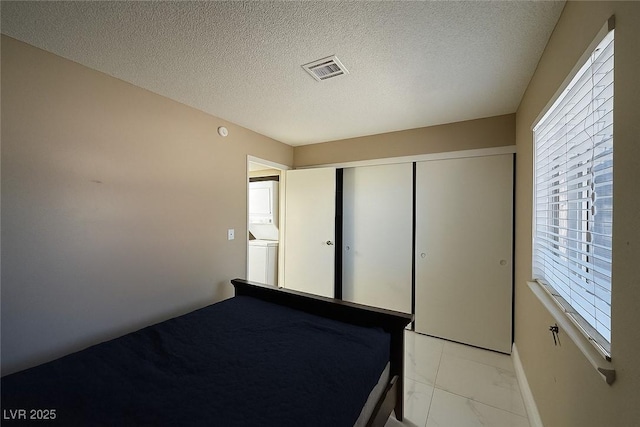 4420 Rich Dr Unit B, Las Vegas, NV 89102 - unfurnished bedroom featuring light marble finish flooring, a textured ceiling, a closet, and stacked washer / dryer